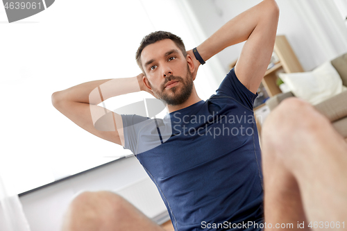 Image of man making abdominal exercises at home