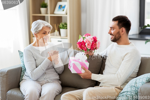 Image of son giving present and flowers to senior mother