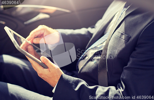 Image of senior businessman with tablet pc driving in car