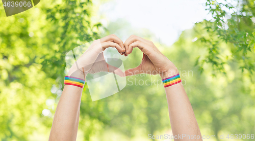 Image of male hands with gay pride wristbands showing heart