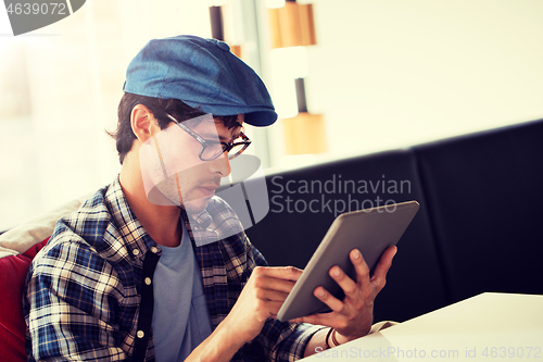 Image of man with tablet pc sitting at cafe table