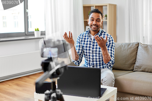 Image of male blogger with camera videoblogging at home