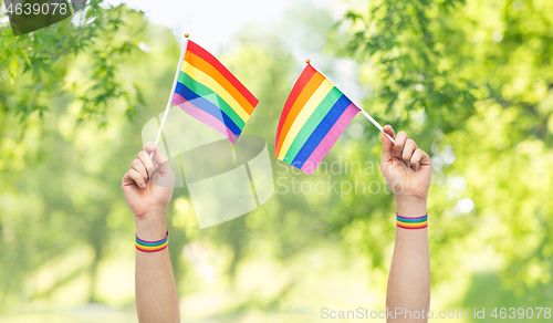 Image of hands with gay pride rainbow flags and wristbands