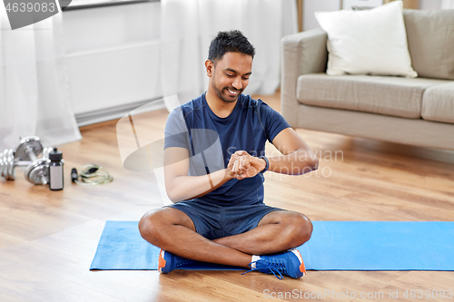 Image of smiling indian man with fitness tracker at home