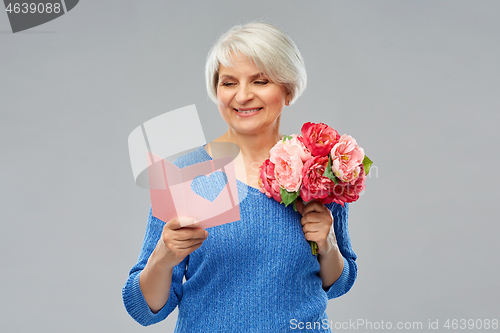 Image of happy senior woman with flowers and greeting card