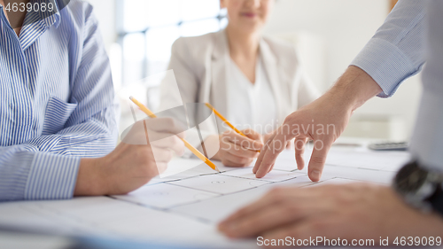 Image of close up of architects with blueprint at office