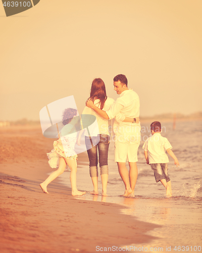 Image of happy young family have fun on beach at sunset