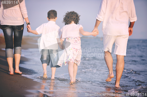 Image of happy young family have fun on beach at sunset