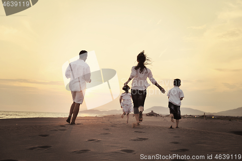 Image of happy young family have fun on beach at sunset