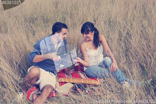 Image of happy couple enjoying countryside picnic in long grass