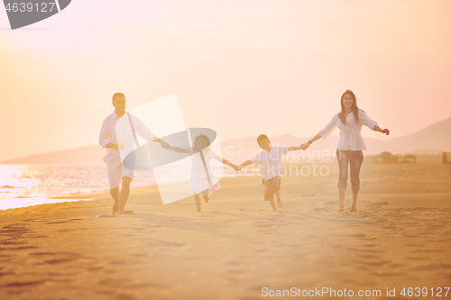 Image of happy young family have fun on beach at sunset