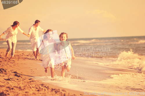 Image of happy family playing with dog on beach