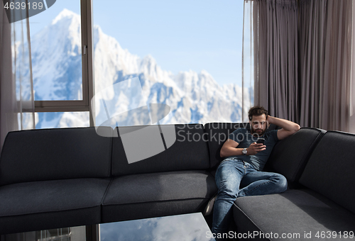Image of young casual man using a mobile phone at home