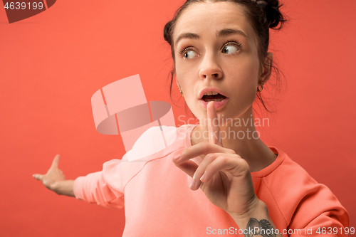 Image of Beautiful woman looking suprised isolated on coral