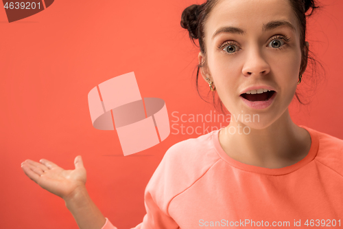 Image of Beautiful woman looking suprised isolated on coral