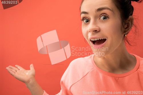 Image of Beautiful woman looking suprised isolated on coral