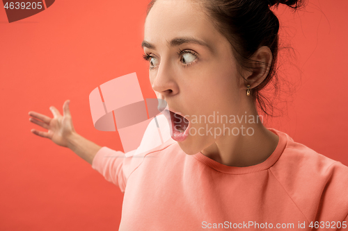 Image of Beautiful woman looking suprised isolated on coral