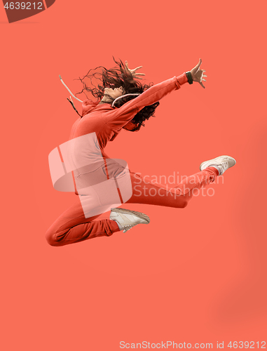 Image of Freedom in moving. Pretty young woman jumping against coral background