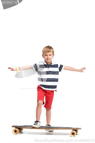 Image of Full length portrait of an adorable young boy riding a skateboard isolated against white background