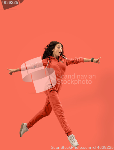 Image of Freedom in moving. Pretty young woman jumping against coral background