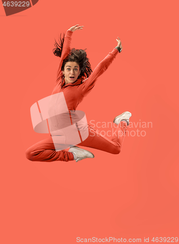 Image of Freedom in moving. Pretty young woman jumping against coral background