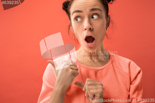 Image of Beautiful woman looking suprised isolated on coral