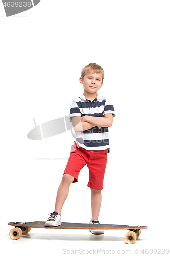 Image of Full length portrait of an adorable young boy riding a skateboard isolated against white background