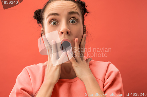 Image of Beautiful woman looking suprised isolated on coral