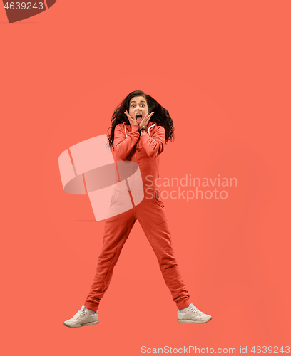 Image of Freedom in moving. Pretty young woman jumping against coral background