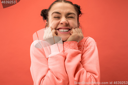 Image of The happy woman standing and smiling against coral background.