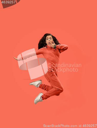 Image of Freedom in moving. Pretty young woman jumping against coral background