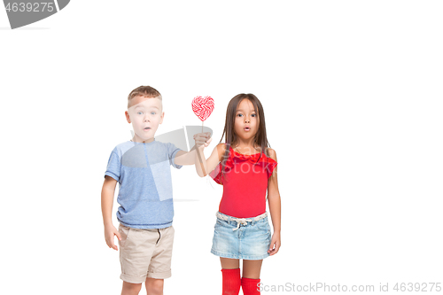 Image of Full length portrait of cute little kids in stylish clothes looking at camera and smiling with candy