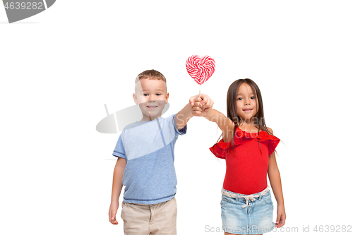 Image of Full length portrait of cute little kids in stylish clothes looking at camera and smiling with candy