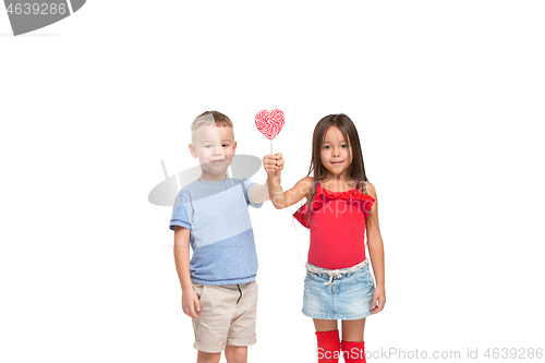 Image of Full length portrait of cute little kids in stylish clothes looking at camera and smiling with candy
