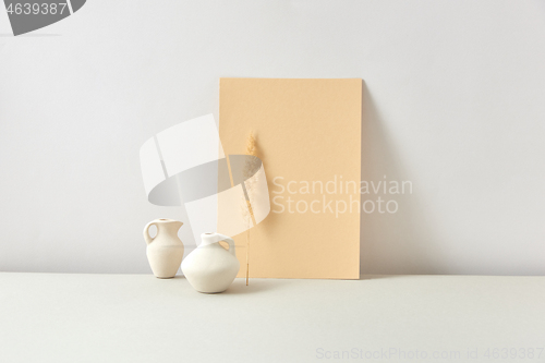 Image of Eco composition from ceramic vases with dry twig and vertical paper sheet.
