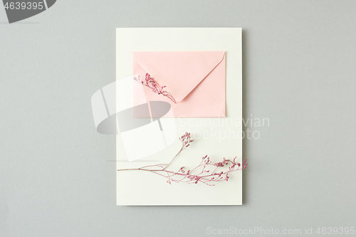 Image of Holiday card from flower twigs and paper envelope on a light grey background.