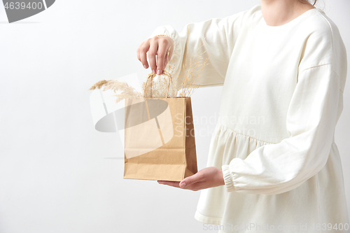 Image of Female holds in her hands paper eco bag with dry natural plant twigs.