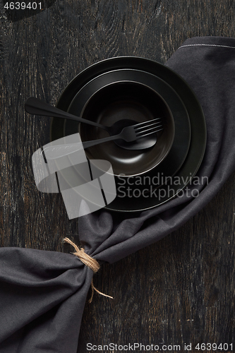 Image of Served kitchen table with cookware and textile napkin in black colors.