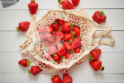 Image of Fresh strawberries in eco-friendly package on white wooden background. Vegetarian organic meal