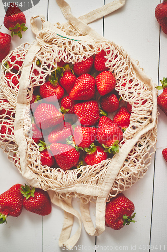 Image of Fresh strawberries in eco-friendly package on white wooden background. Vegetarian organic meal