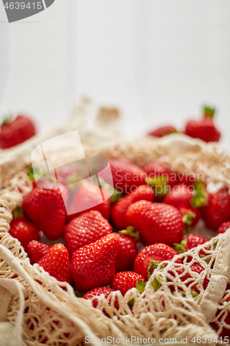 Image of Fresh strawberries in eco-friendly package on white wooden background. Vegetarian organic meal