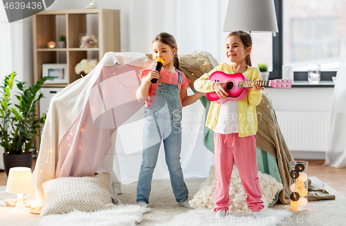 Image of girls with guitar and microphone playing at home