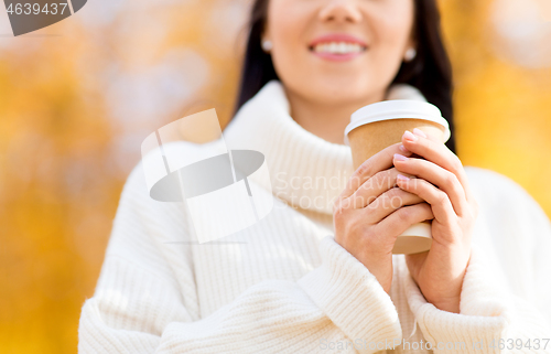 Image of happy young woman drinking coffee in autumn park