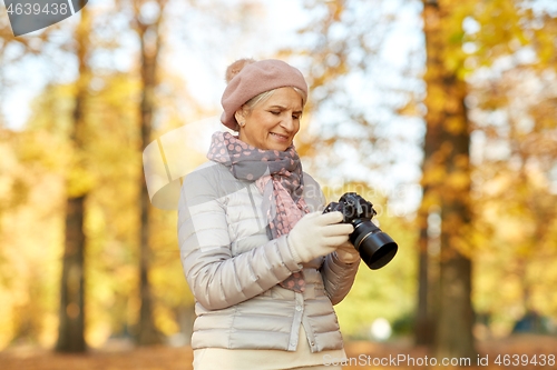 Image of senior woman with photo camera at autumn park