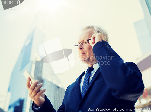 Image of senior businessman with smartphone in city