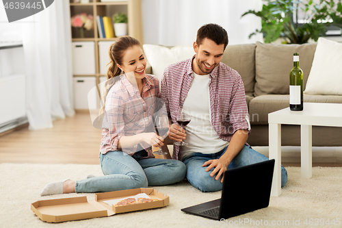 Image of happy couple with laptop drinking red wine at home