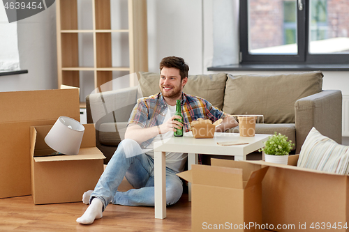 Image of smiling man drinking beer and eating at new home