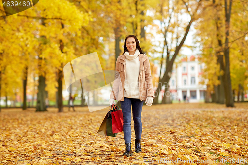 Image of woman with shopping bags in autumn park