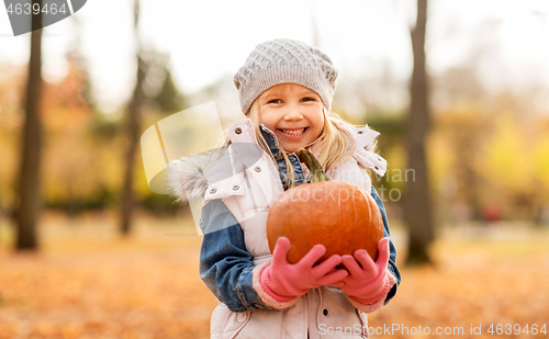 Image of happy little girl with pumpkin at autumn park