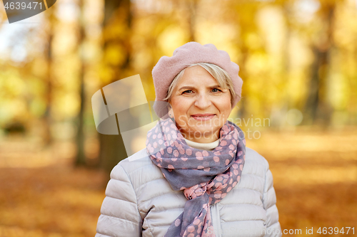 Image of portrait of happy senior woman at autumn park